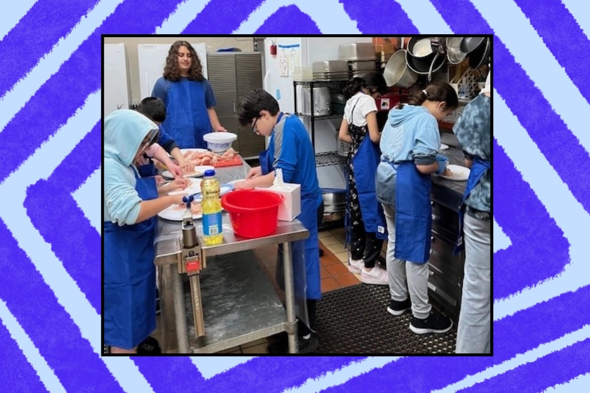 A diverse group of young individuals wearing blue aprons are engaged in food preparation in a kitchen setting, demonstrating teamwork and community service. They are involved in activities such as cutting and mixing food items, highlighting the importance of volunteer opportunities and civic learning.